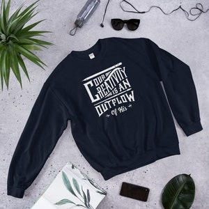 Op de afbeelding: Een donkerblauw sweatshirt met een wit grafisch ontwerp met de tekst "Onze creativiteit is een uitstroom van Hem".