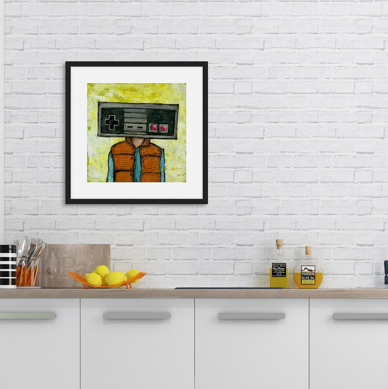 May include: A framed illustration of a person with a retro video game controller for a head. The person is wearing a blue shirt and an orange vest. The background is a yellow and green color.