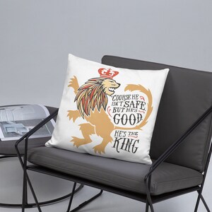 Puede incluir: Almohada blanca con un gr&aacute;fico de un le&oacute;n con una corona. El le&oacute;n es dorado y el texto dice "Claro que no es seguro, pero es bueno. &Eacute;l es el rey."