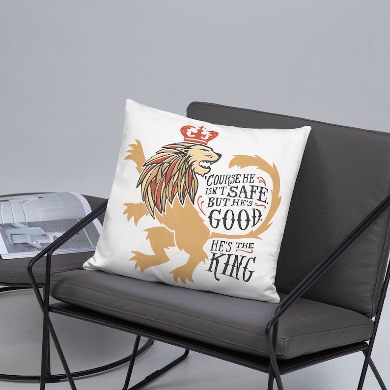 Puede incluir: Almohada blanca con un gr&aacute;fico de un le&oacute;n con una corona. El le&oacute;n es dorado y el texto dice "Claro que no es seguro, pero es bueno. &Eacute;l es el rey."