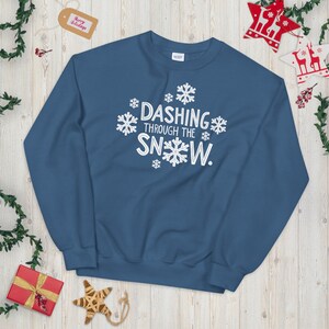 May include: A blue sweatshirt with white snowflakes and the text "Dashing Through The Snow."