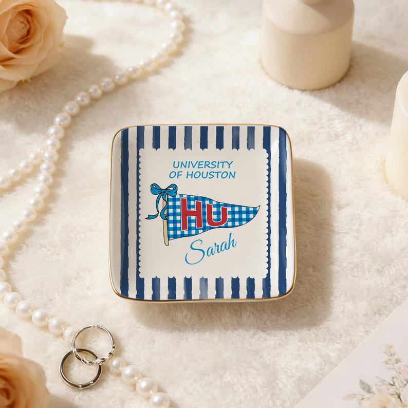 May include: Square ceramic trinket dish with blue and white striped border and gold trim. Features a pennant design with "UNIVERSITY OF HOUSTON" and "HU" in red and blue, with the name "Sarah" below.