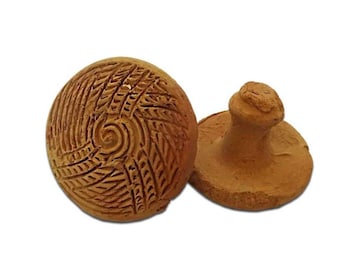 Puede incluir: Dos sellos de arcilla tallados a mano, color terracota. Un sello es redondo con un patrón de espiral y hojas. El otro sello tiene un mango y una base redonda. Los sellos probablemente se utilizan para imprimir diseños.