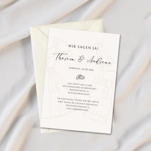 May include: A wedding invitation with a cream-colored envelope and a matching card. The card features the text "WIR SAGEN JA!" and the names "Theresa & Andreas" in elegant script. Additional text includes the date and location details.