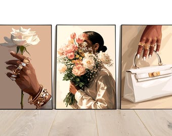 May include: Set of three framed art prints. One features a hand holding a white rose, adorned with rings and bracelets. Another shows a person holding a bouquet of pink and white flowers. The third depicts a hand with rings holding a white handbag.