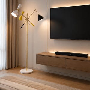 May include: A floor lamp with a gold-toned metal stand and a white marble base. The lamp features three adjustable arms with conical shades in white, yellow, and black, each containing a light bulb. The lamp stands upright on a flat surface.