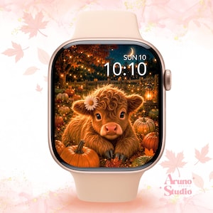 May include: A light beige smartwatch featuring a digital display with a high-resolution image of a fluffy brown calf with a white flower on its head, surrounded by orange pumpkins and autumn foliage under a night sky with a crescent moon and lanterns.