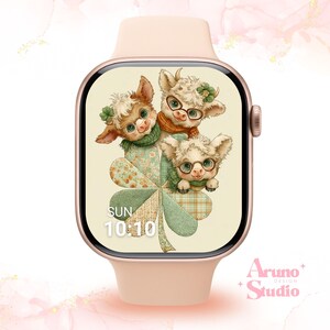 Op de afbeelding: Een blush-kleurige smartwatch met een klaverontwerp met drie cartoonkoeien met brillen en sjaals. De wijzerplaat toont de tijd als 10:10 en de dag als zondag. Het horloge is van Aruno Design Studio.