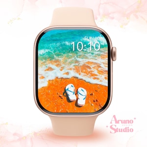 May include: A rose gold smartwatch displaying a beach scene. The screen shows a sandy beach, ocean waves, and flip-flops. The time displayed is 10:10 on Sunday. The watch has a pale pink strap.