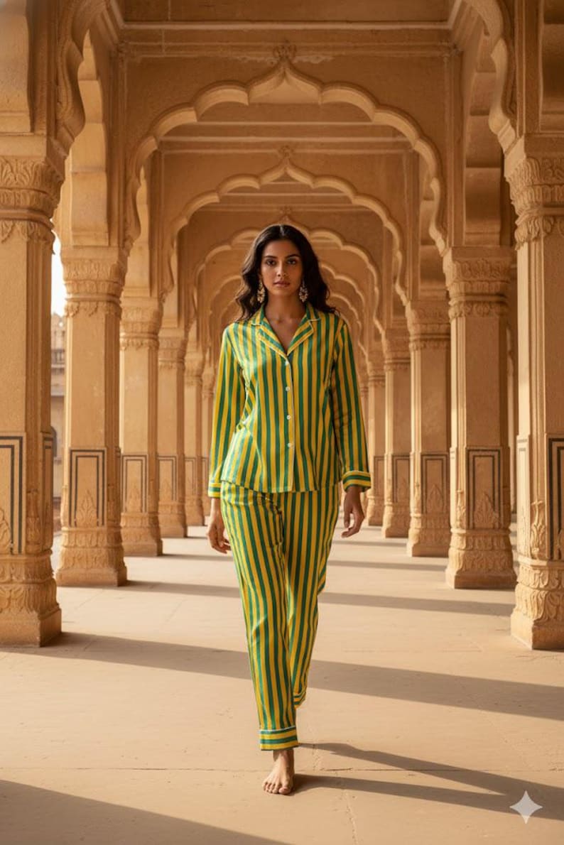 Peut inclure: Une personne porte un ensemble de pyjama &agrave; rayures vertes et jaunes. La chemise boutonn&eacute;e &agrave; manches longues et le pantalon assorti pr&eacute;sentent des rayures verticales. Le pyjama est bord&eacute; d'une couleur contrastante. L'arri&egrave;re-plan pr&eacute;sente une colonnade avec des plafonds vo&ucirc;t&eacute;s.