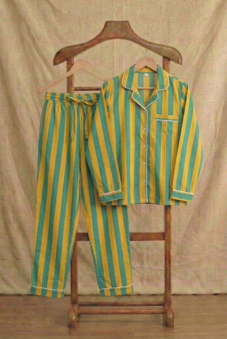Peut inclure: Ensemble de pyjama &agrave; rayures jaunes et turquoise. La chemise boutonn&eacute;e &agrave; manches longues et le pantalon assorti sont pr&eacute;sent&eacute;s sur un cintre en bois. Le pyjama a des bordures blanches et une taille &agrave; cordon. L'ensemble est en tissu doux et l&eacute;ger.