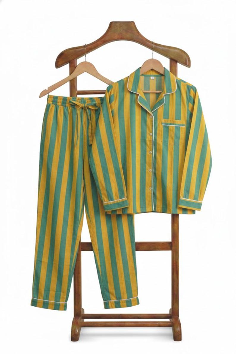 Peut inclure: Un ensemble de pyjama &agrave; rayures verticales jaunes et vertes. L'ensemble comprend une chemise &agrave; manches longues et un pantalon, avec des bordures blanches. Le pyjama est pr&eacute;sent&eacute; sur un cintre en bois.