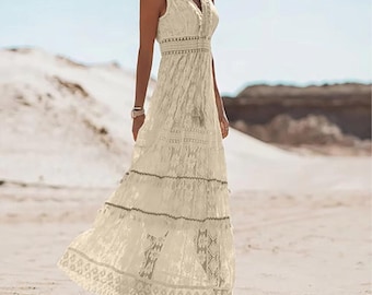 May include: A cream-coloured sleeveless maxi dress with a V-neck and detailed lace. The dress has a tiered skirt and a flowing shape, suitable for a beach or summer event. The dress is made of a lightweight fabric.