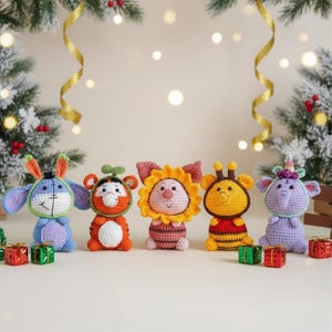 Könnte beinhalten: Fünf handgefertigte Häkelfiguren von Tieren, darunter ein Hase, ein Tiger, ein Löwe, eine Biene und ein Elefant. Jede Figur hat einzigartige Merkmale. Kleine Geschenkboxen sind vor den Figuren platziert, mit einem Weihnachtsbaum im Hintergrund.