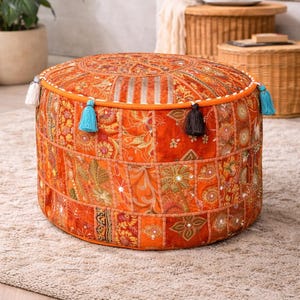 Può includere: Pouf rotondo arancione patchwork con nappe decorative. Il pouf presenta una varietà di tessuti fantasia nei toni dell'arancione, dell'oro e del verde. Il pouf misura circa 46 cm di diametro e 36 cm di altezza.