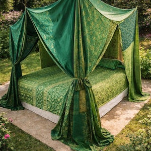 Może przedstawiać: Łóżko z baldachimem z zielonej i złotej tkaniny we wzory. Łóżko znajduje się na zewnątrz, otoczone zielenią i kamiennym patio. Baldachim i pościel mają kwiatowy wzór.