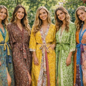 Może przedstawiać: Pięć kobiet w kolorowych, wzorzystych jedwabnych szlafrokach. Szlafroki mają różne wzory w odcieniach niebieskiego, brązowego, żółtego, zielonego i pomarańczowego. Każdy szlafrok jest zawiązany w talii pasującym szarfą. Kobiety uśmiechają się w ogrodzie.