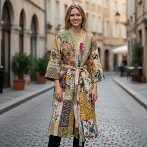 Könnte beinhalten: Langer Patchwork-Bademantel in Beige-, Braun- und Grüntönen mit floralen und geometrischen Mustern. Der Bademantel hat einen passenden Gürtel und wird im Freien getragen. Der Bademantel ist etwa 140 cm lang.