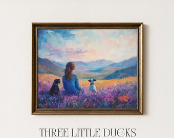 May include: A framed painting depicts a person with two dogs in a field of purple flowers, overlooking a mountain range. The sky is a blend of blues, pinks, and oranges. The painting is signed "THREE LITTLE DUCKS - ART & DESIGN -."