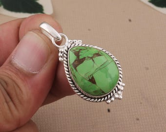 May include: A teardrop-shaped pendant with a vibrant green stone and brown veining, set in a silver-colored metal frame. The pendant has a twisted rope border and decorative accents. The bail is also silver-colored.
