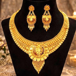 Puede incluir: Un collar de oro y un par de pendientes a juego. El collar presenta una banda ancha y texturizada con un gran colgante central ornamentado y cadenas doradas colgantes. Los pendientes reflejan el diseño del colgante con partes circulares.