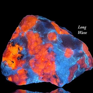 May include: A vibrant, glowing rock formation with a striking contrast of orange and blue hues. The text "Long Wave" is visible. The rock's surface has a textured appearance, set against a black background.
