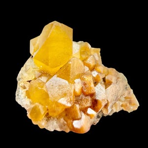 Pode incluir: Um aglomerado de cristais de quartzo amarelo-dourado com uma estrutura cristalina. Os cristais têm uma aparência facetada e estão dispostos sobre um fundo escuro. A formação mineral tem uma superfície áspera e texturizada.