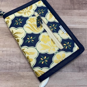 Puede incluir: Una bolsa azul marino con cremallera con un patrón floral dorado y verde. La bolsa tiene un bolsillo con cremallera en la parte delantera y el texto "Stitch & Sew" está impreso en la parte delantera.