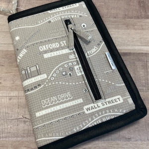 May include: A gray zippered wallet with a map design featuring street names like "Wall Street", "Oxford St", and "Ocean Drive". The wallet has a black zipper and a black border.
