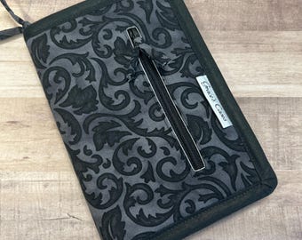 May include: A black zippered wallet with a gray and black floral pattern. The wallet has a zippered pocket on the front and the text "Grace's Creations" is printed on the side.