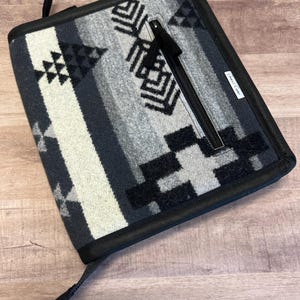 May include: Black and white patterned zippered pouch with a black zipper pull and a black leather tag that says "Great Lakes".