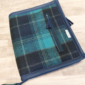 May include: A blue and green plaid zippered pouch with a black leather trim and the text "Craft Crew" on the front.
