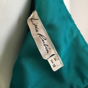 May include: A white tag with black text that reads "J.janie  Culin" and "Size 10" on a teal fabric background.