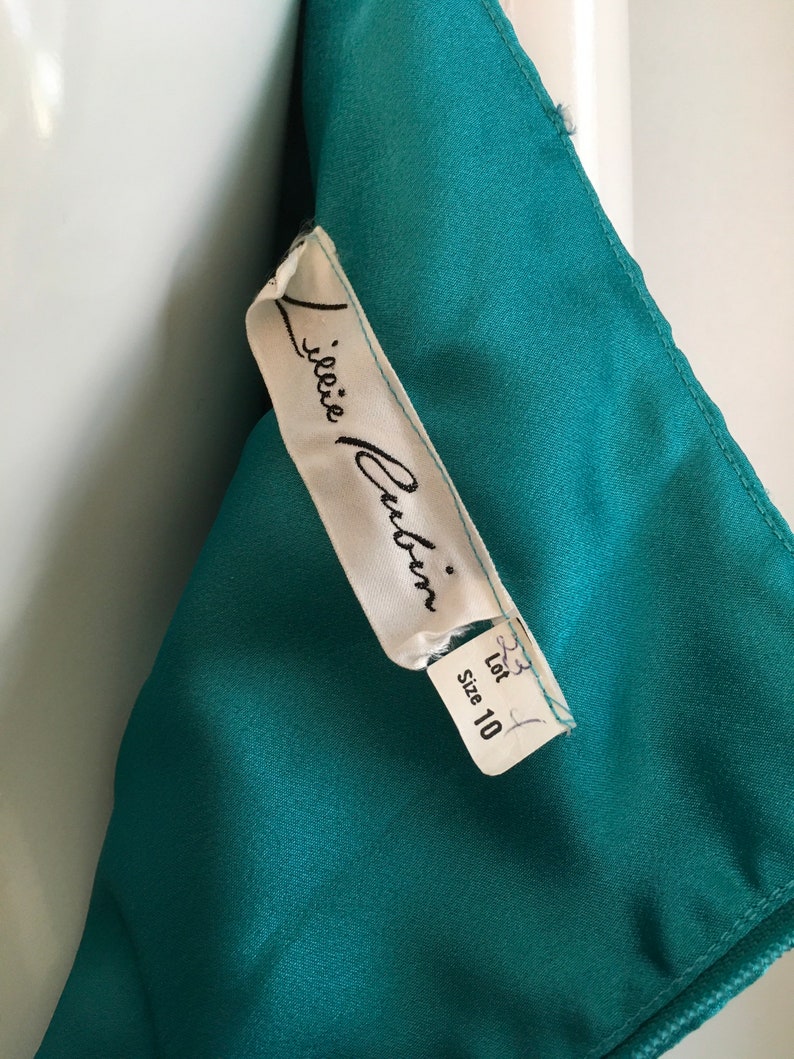 May include: A white tag with black text that reads "J.janie  Culin" and "Size 10" on a teal fabric background.