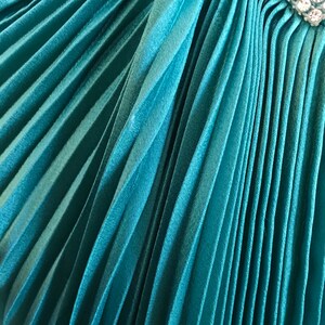 May include: Teal pleated fabric with a row of clear rhinestones.
