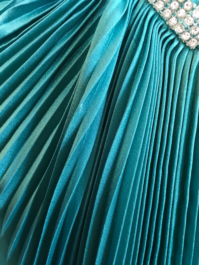 May include: Teal pleated fabric with a row of clear rhinestones.