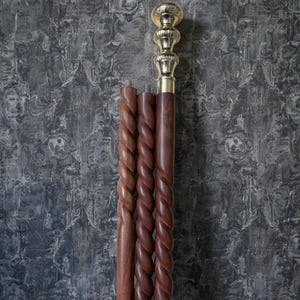 May include: A wooden walking cane with a gold-coloured handle and a decorative, twisted wood shaft. The cane is shown disassembled, with the handle and three separate shaft sections. The cane's handle has a bulbous design.