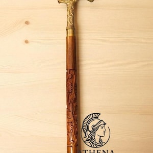 May include: A decorative walking cane with a brass handle and accents. The handle is curved and features intricate floral detailing. The wooden shaft is carved with floral patterns. The cane is approximately 36 inches long.