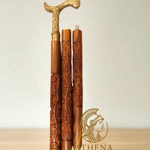Pode incluir: Bengala de madeira com cabo de latão e entalhes florais. A bengala é marrom com um cabo curvo. O cabo é de cor dourada clara. A bengala é em três partes, com a seção do meio com entalhes florais detalhados. Aproximadamente 91 cm de altura.