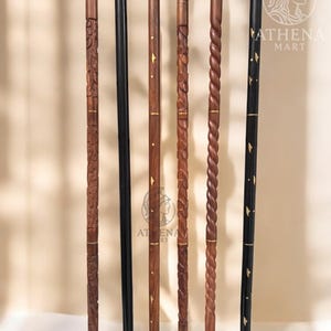 May include: A collection of walking canes with various designs. The canes are made of wood and metal, with intricate carvings, spiral patterns, and inlaid details. One cane is solid black, while others are brown and feature gold accents. The Athena Mart logo is visible.