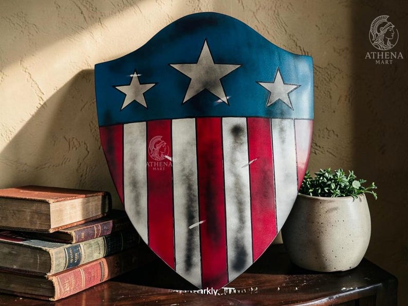 May include: A shield with a blue top section featuring three white stars and a red and white striped bottom. The shield has a distressed, vintage appearance. The Athena Mart logo is visible on the shield. The shield is displayed on a wooden surface.