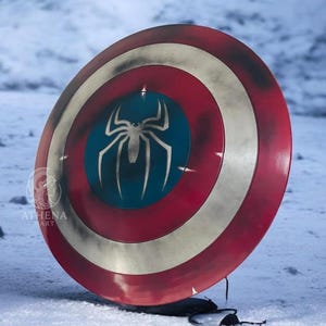 Puede incluir: Un escudo redondo con un dise&ntilde;o rojo, blanco y azul. El escudo presenta un centro azul con un emblema de ara&ntilde;a blanco. El escudo es un accesorio, probablemente para cosplay o exhibici&oacute;n.