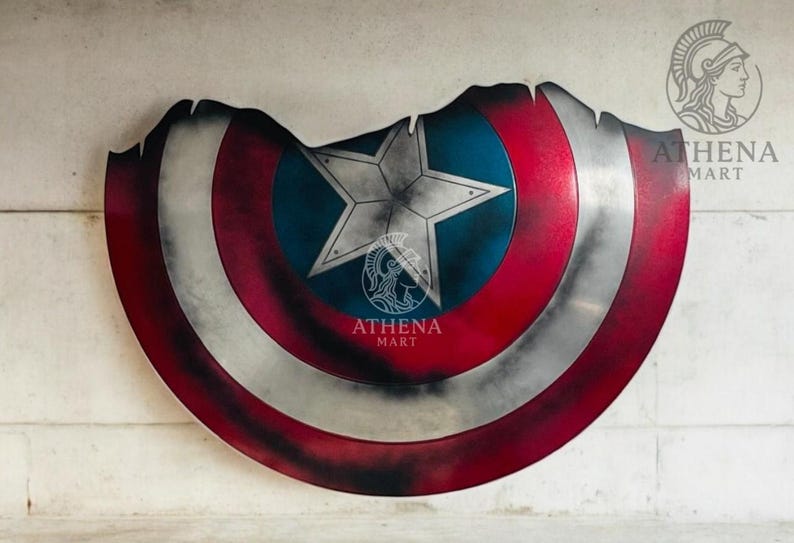 May include: A distressed Captain America shield with a red, white, and blue color scheme. The shield features a central blue circle with a white star, surrounded by red and white stripes. The shield has a worn, battle-damaged appearance.