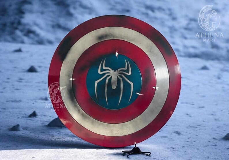 Puede incluir: Escudo redondo con una combinaci&oacute;n de colores rojo, blanco y azul. El escudo presenta un gran emblema de ara&ntilde;a blanca sobre un c&iacute;rculo azul en el centro. El escudo tiene una apariencia desgastada, lo que sugiere una est&eacute;tica desgastada por la batalla.