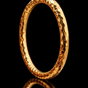 May include: A circular bangle bracelet with a metallic copper finish and a hammered, textured surface. The jewellery piece features a reflective, uneven exterior that catches light. The text 'accents 1copper' is visible in the upper right corner.