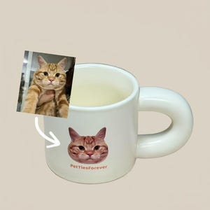 以下が含まれることがあります： 大きな丸い取っ手が付いた白いセラミックマグ。マグには猫の顔のグラフィックと「PettiesForever」の文字が描かれています。マグの隣には猫の画像があります。マグは猫好きの方に最適です。