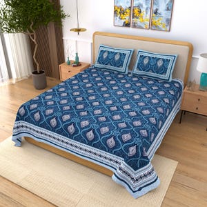 May include: A bed sheet set featuring a deep blue and white repeating teardrop pattern with a decorative border. The set includes a large bed sheet and two matching rectangular pillowcases, all displaying a consistent intricate geometric design.