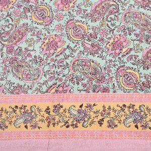 May include: A floral textile featuring a paisley and floral pattern in shades of pink, yellow, and green. The design includes a border with paisley and floral motifs on a yellow background, and a striped pink bottom.