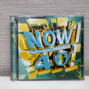 May include: A CD case for "NOW! 40", a double CD compilation of chart hits. The cover features the word "NOW" in large, turquoise 3D letters, with "40" below. The background is yellow and green.