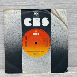 May include: A vintage 45 RPM vinyl record by Johnny Nash, featuring the song "Tears on My Pillow (I Can't Take It)". The record label is orange with black text and the CBS logo. The sleeve is black and white with the CBS logo.